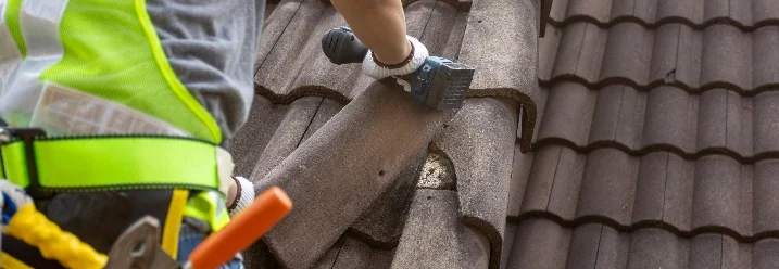 Person repariert Dachziegel